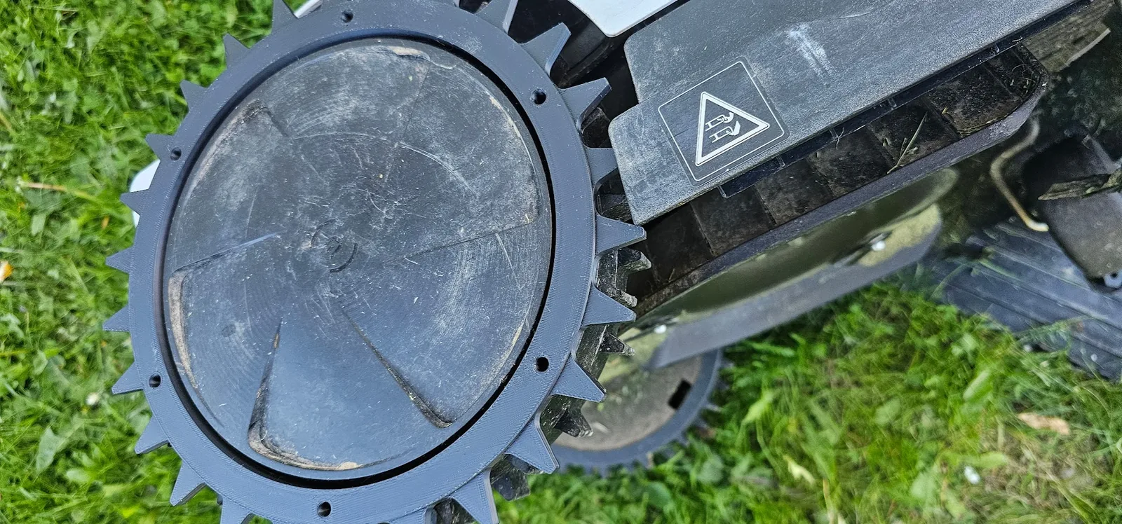 Terrenghjul og piggring montert på robotklipperhjul ute på gresset